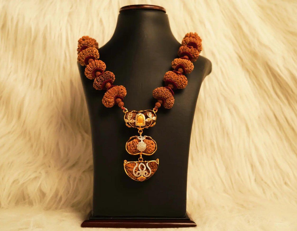 An Indra Mala with gold-capped Rudraksha beads on a display bust