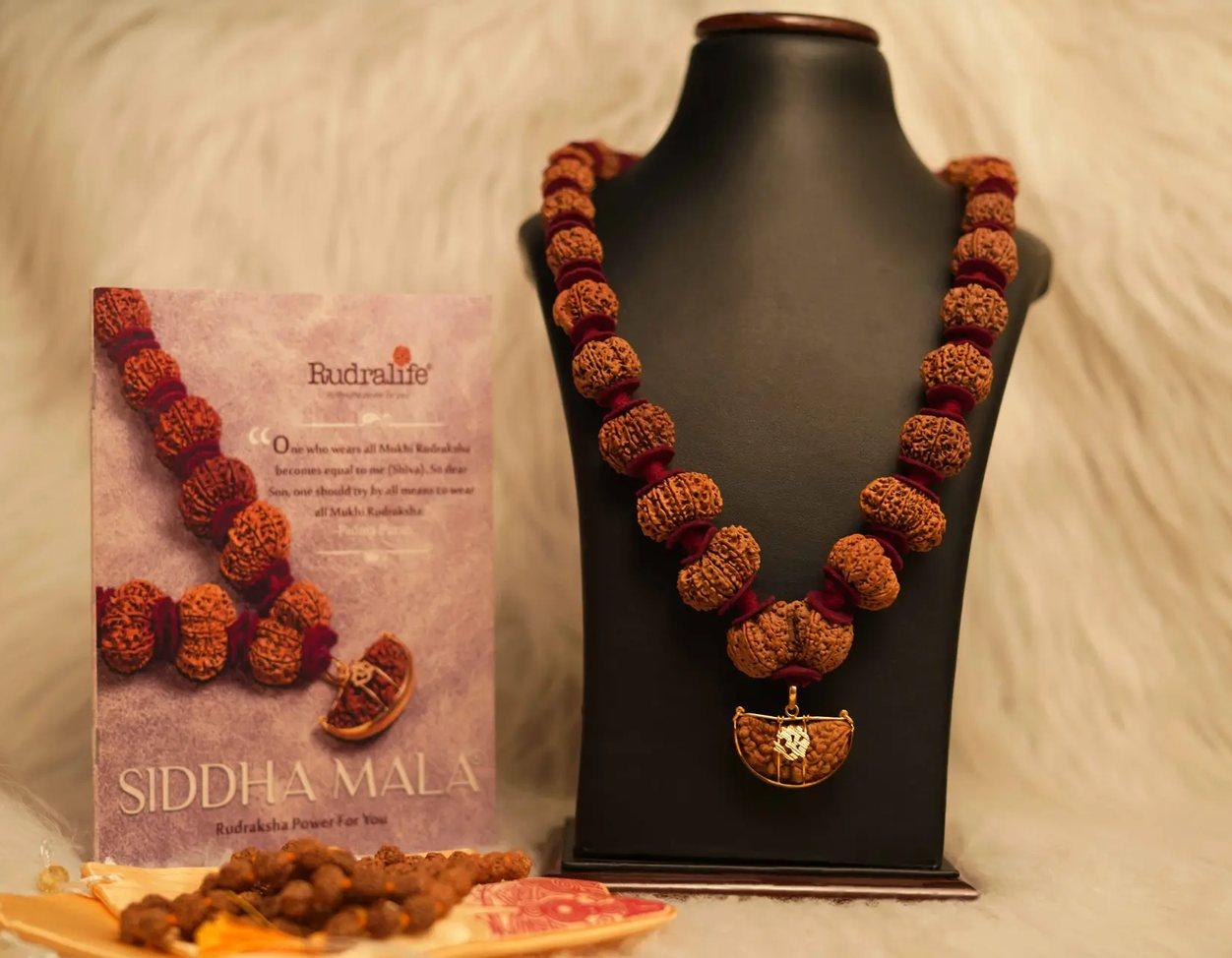 A Siddha Mala on a display bust beside the Rudralife Siddha Mala book